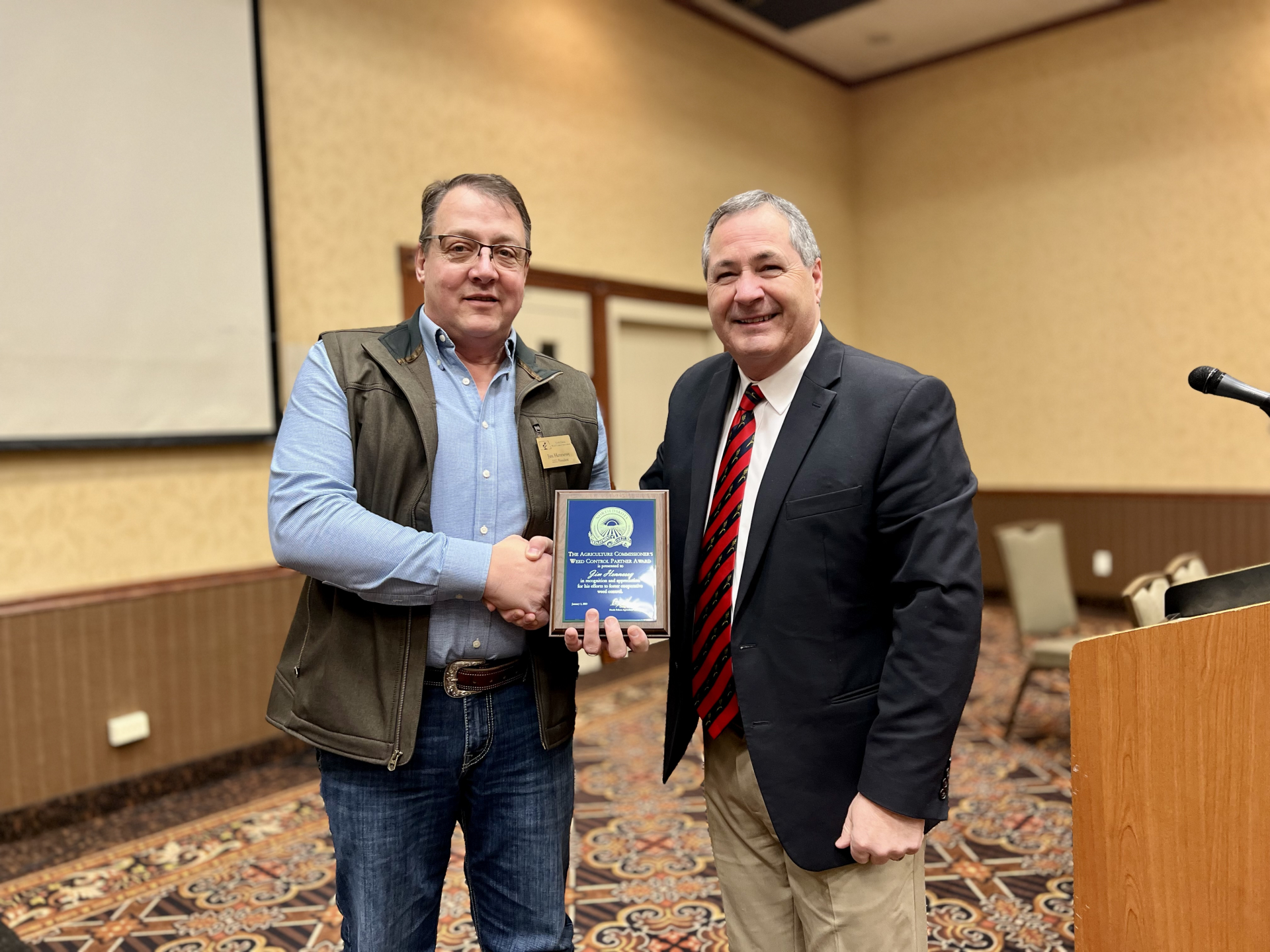 Jim Hennessy receives the 2023 Weed Control Partner Award from North Dakota Agriculture Commissioner Doug Goehring.