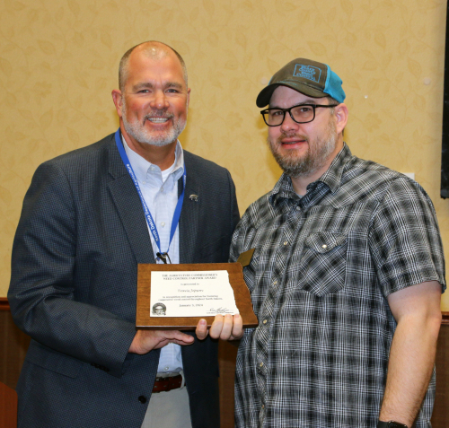 Travis Jepson receives the 2024 Weed Control Partner Award from Deputy Commissioner Tom Bodine